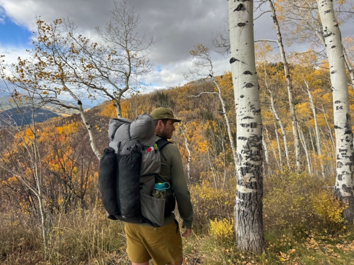 Outdoor Vitals Shadowlight 60 backpack seen from the side as the hiker pauses among golden aspens