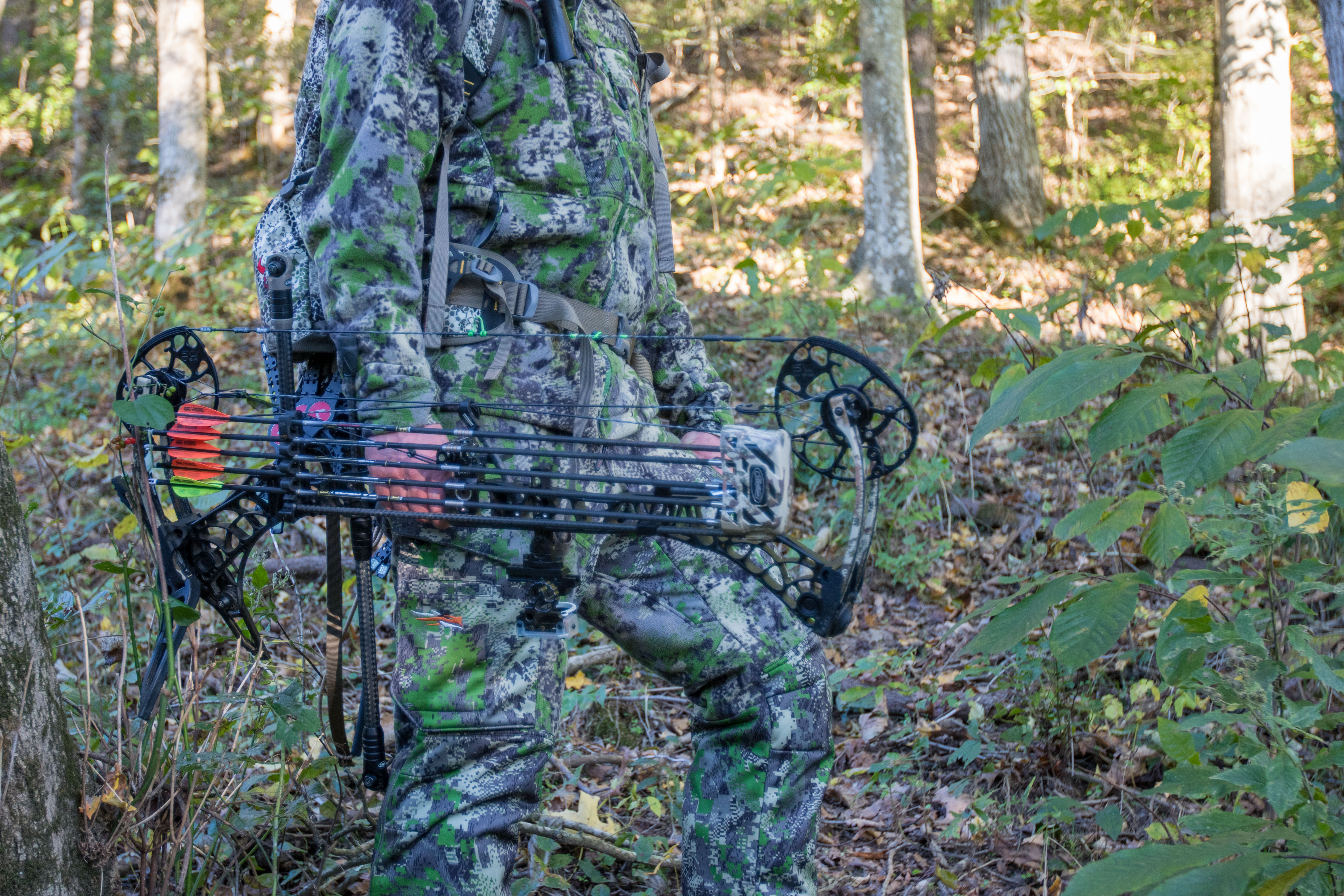 A hunter holding a bow on a hillside in the SITKA Stratus 2,0 System