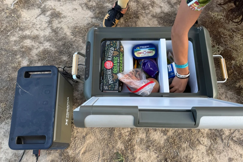 A person reaches into the TRAVOCA Rigel DZ eCooler to grab food while it’s powered at camp