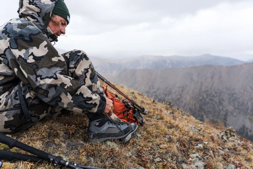 Hunter laces up boot on mountain