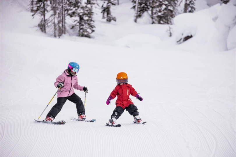 Two young riders ski down hill