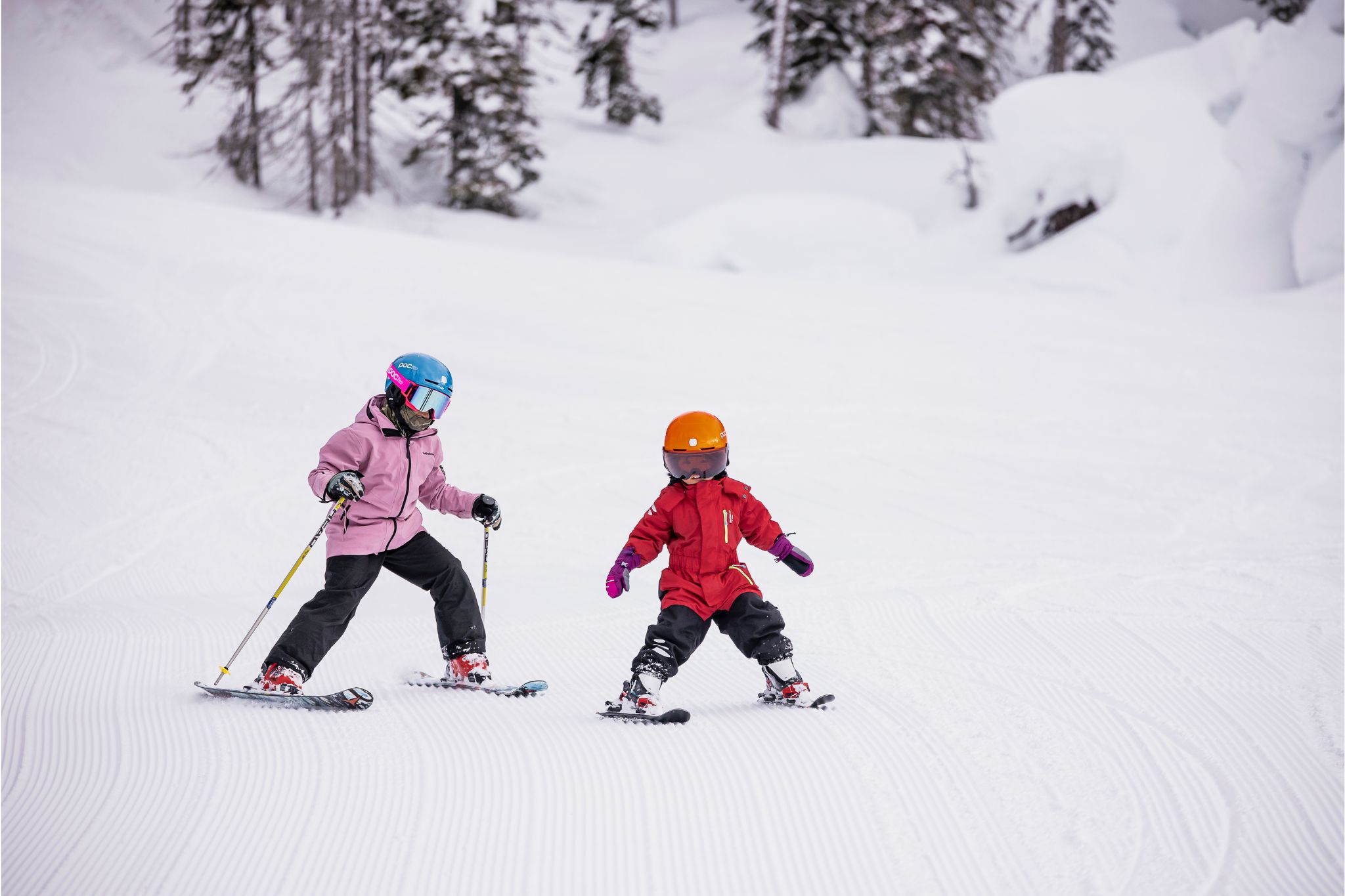 Two young riders ski down hill