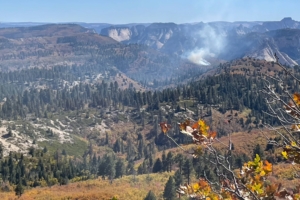 Rocky forest landscape with smoke from fire in the distance