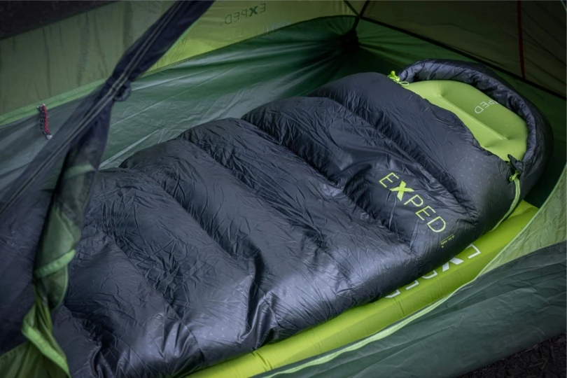 black and green sleeping bag set up in a tent