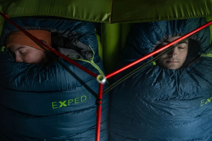 Two people asleep in sleeping bags in a tent