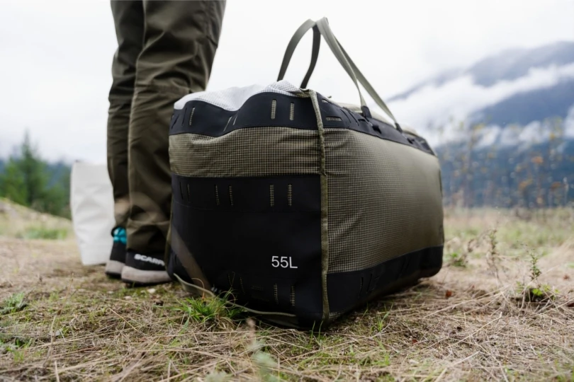 Person stands next to duffel bag on ground