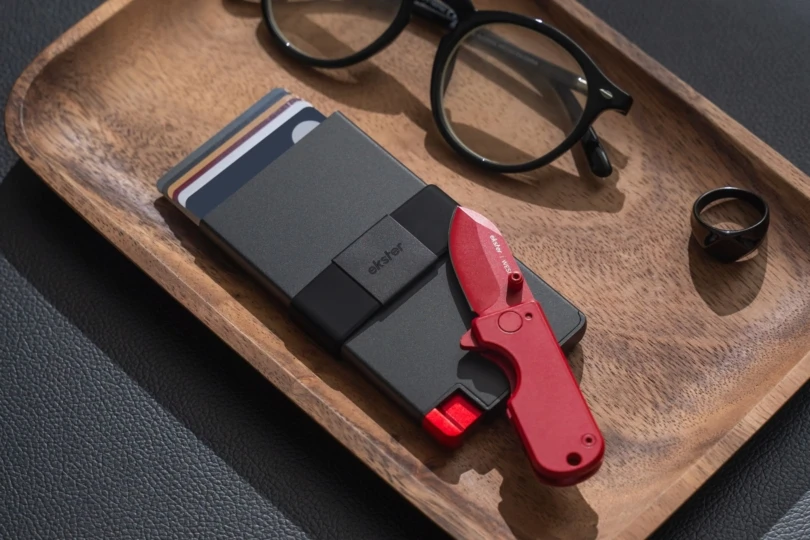 Wallet and knife and glasses on a wooden tray. 
