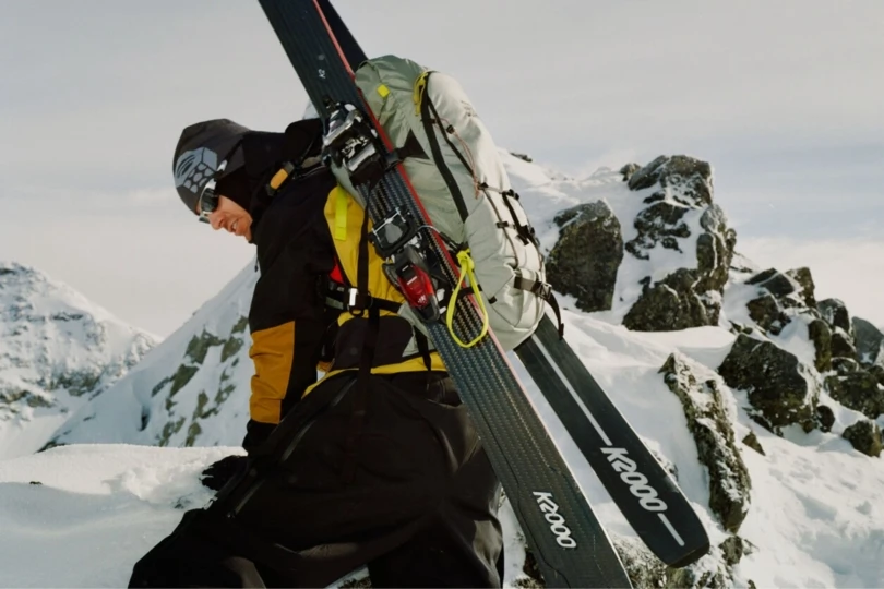 Skier carrying skies up mountain 