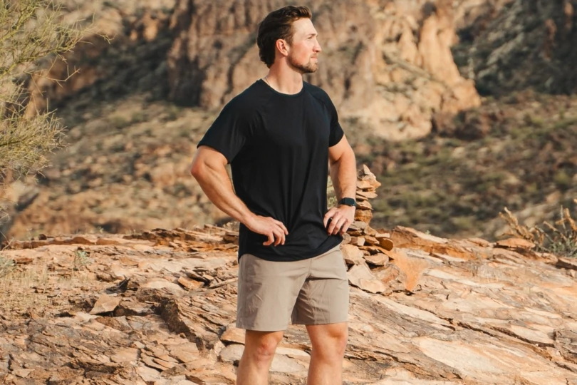 Man in black t-shirt and tan shorts on rocky landscape