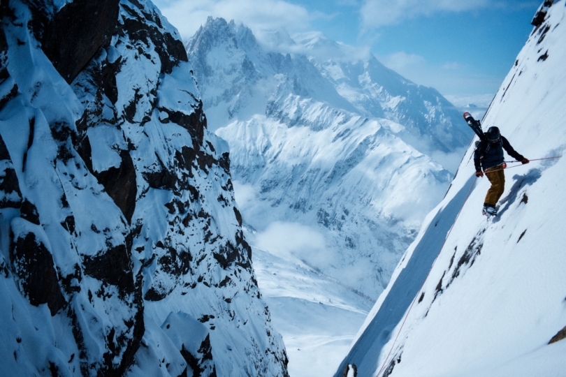 Person rappels down snowy mountain