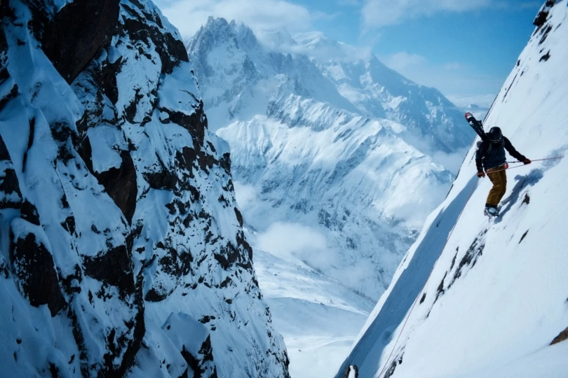 Person rappels down snowy mountain