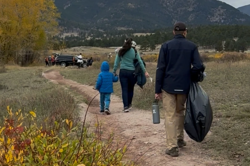 People walk on trail with trash bags