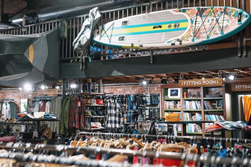 Inside of gear shop with racks of clothing and paddleboard