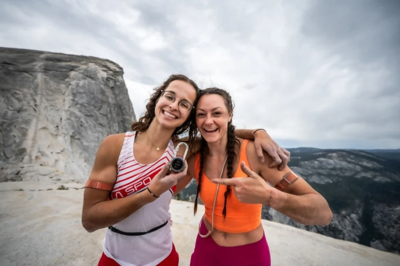 Two women celebrate on top of a mountain