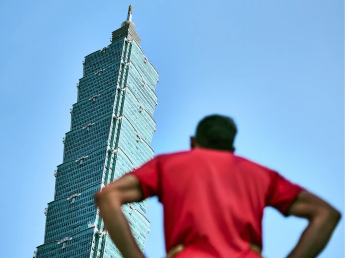 See back of person as they look up at skyscraper