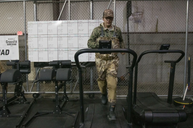 A man running on a treadmill in camo waders
