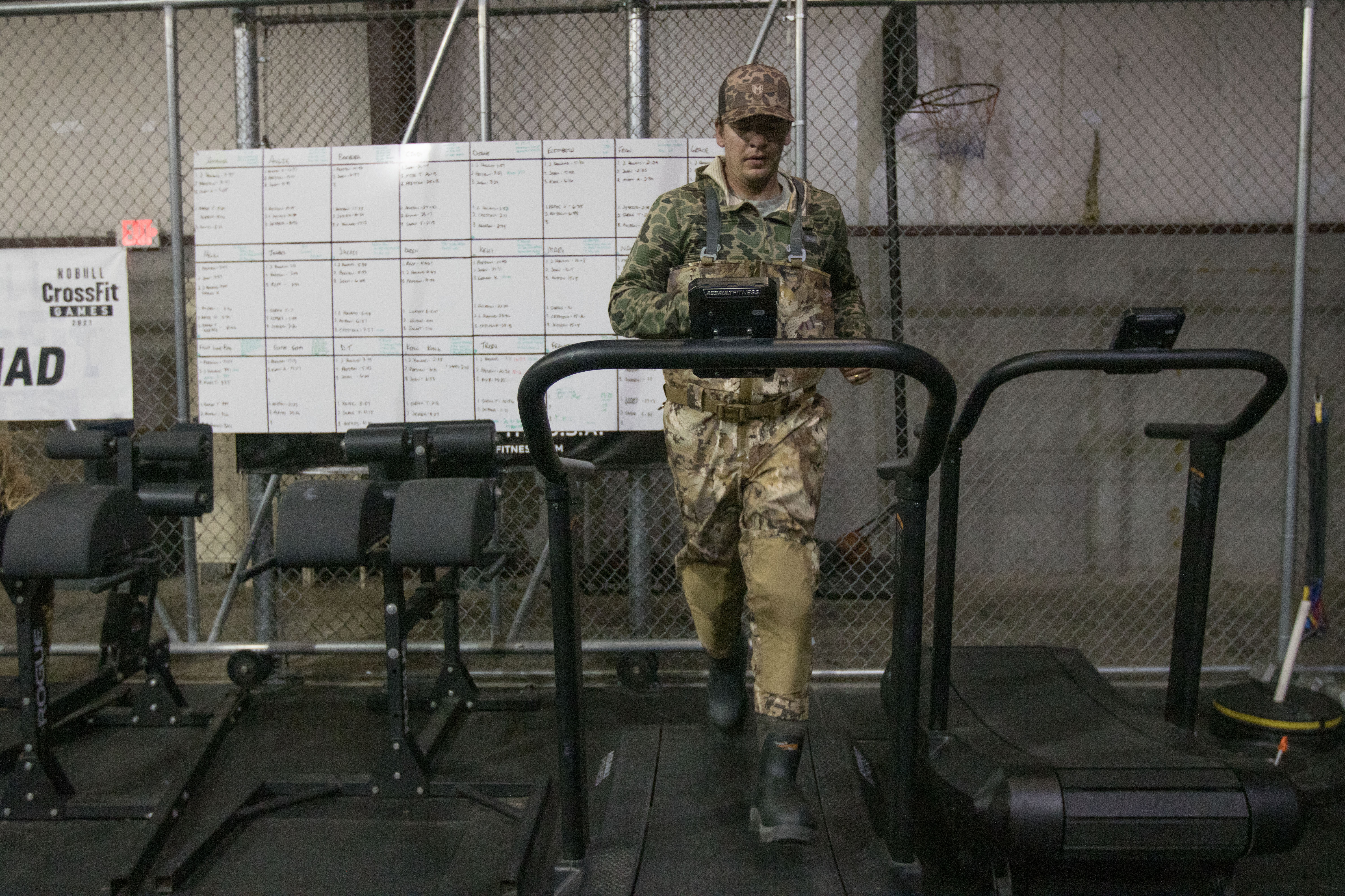 A man running on a treadmill in camo waders