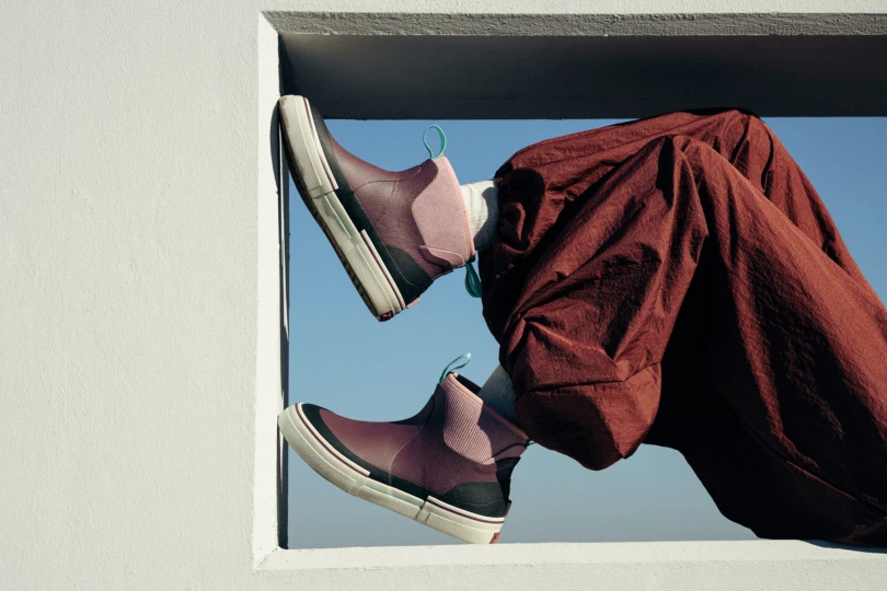 Close up shot of person sitting on ledge wearing rain boots