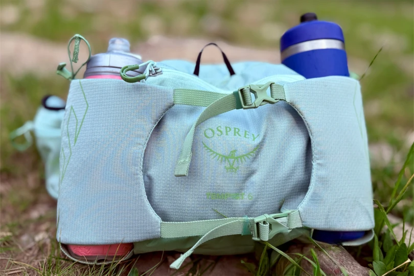 Close-up of the Osprey Tempest 6 Waistpack showing the logo, buckles, and dual water bottle holders