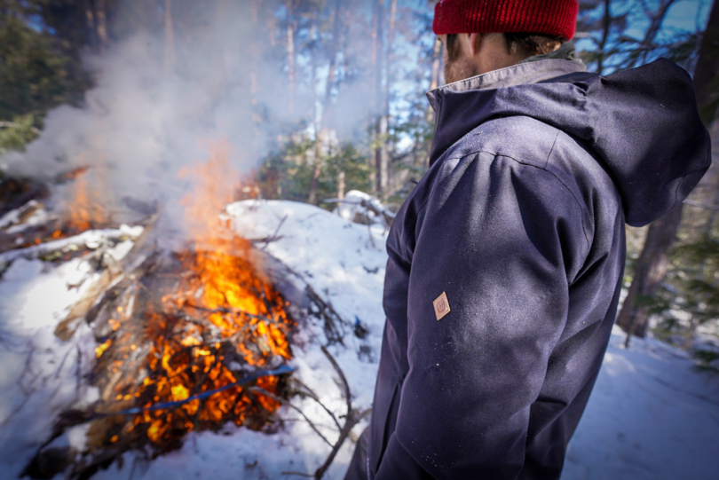 person wearing teren campfire puffy jacket next to bonfire