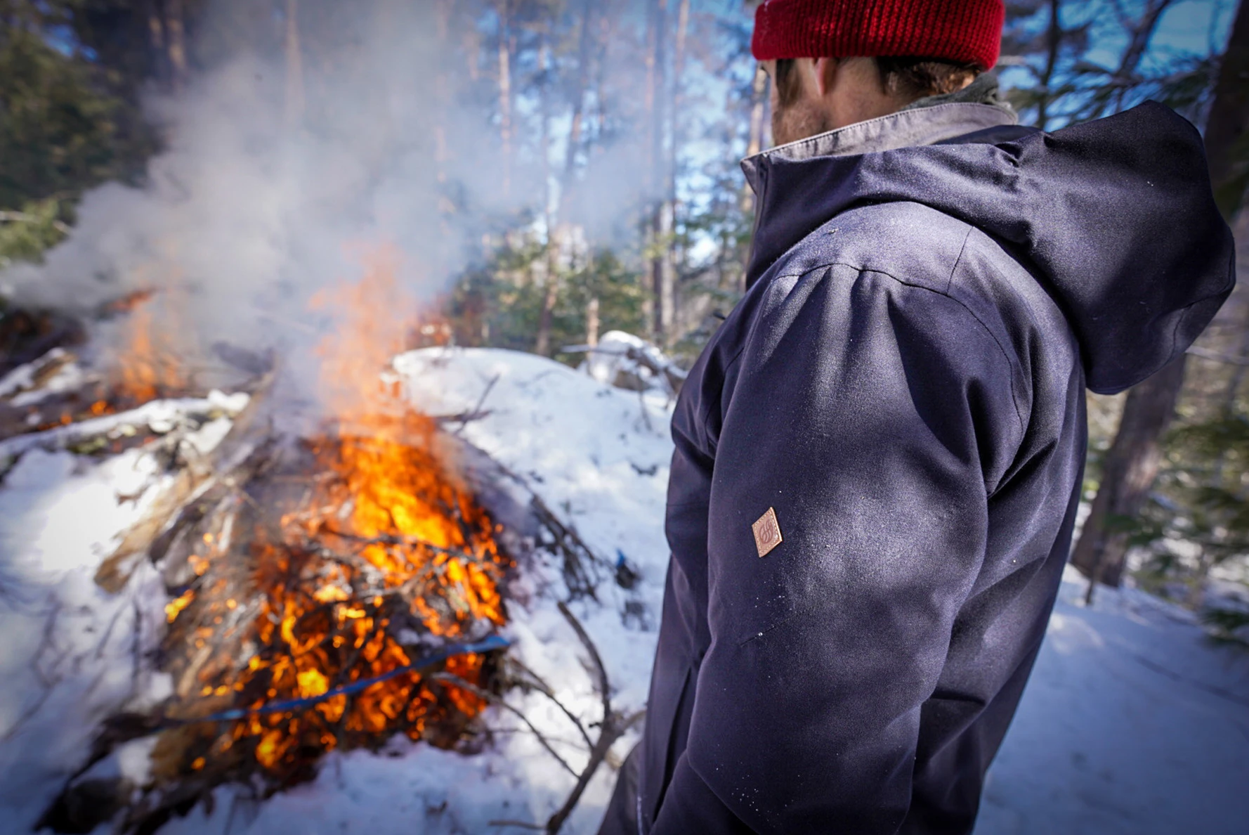 person wearing teren campfire puffy jacket next to bonfire