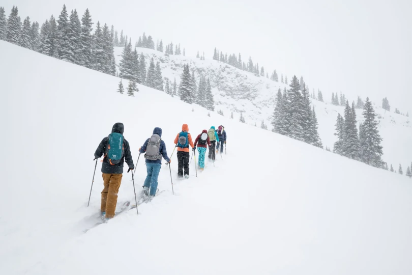 A group of people hiking uphill on skis through deep snow