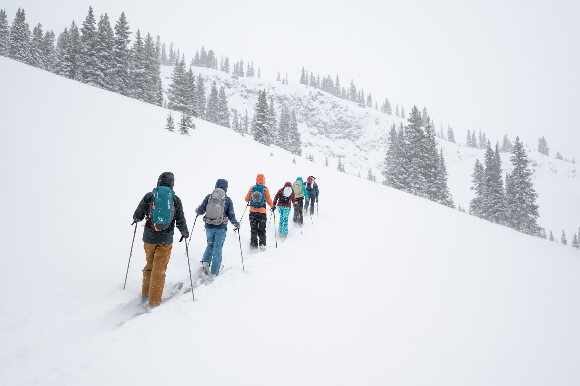 A group of people hiking uphill on skis through deep snow