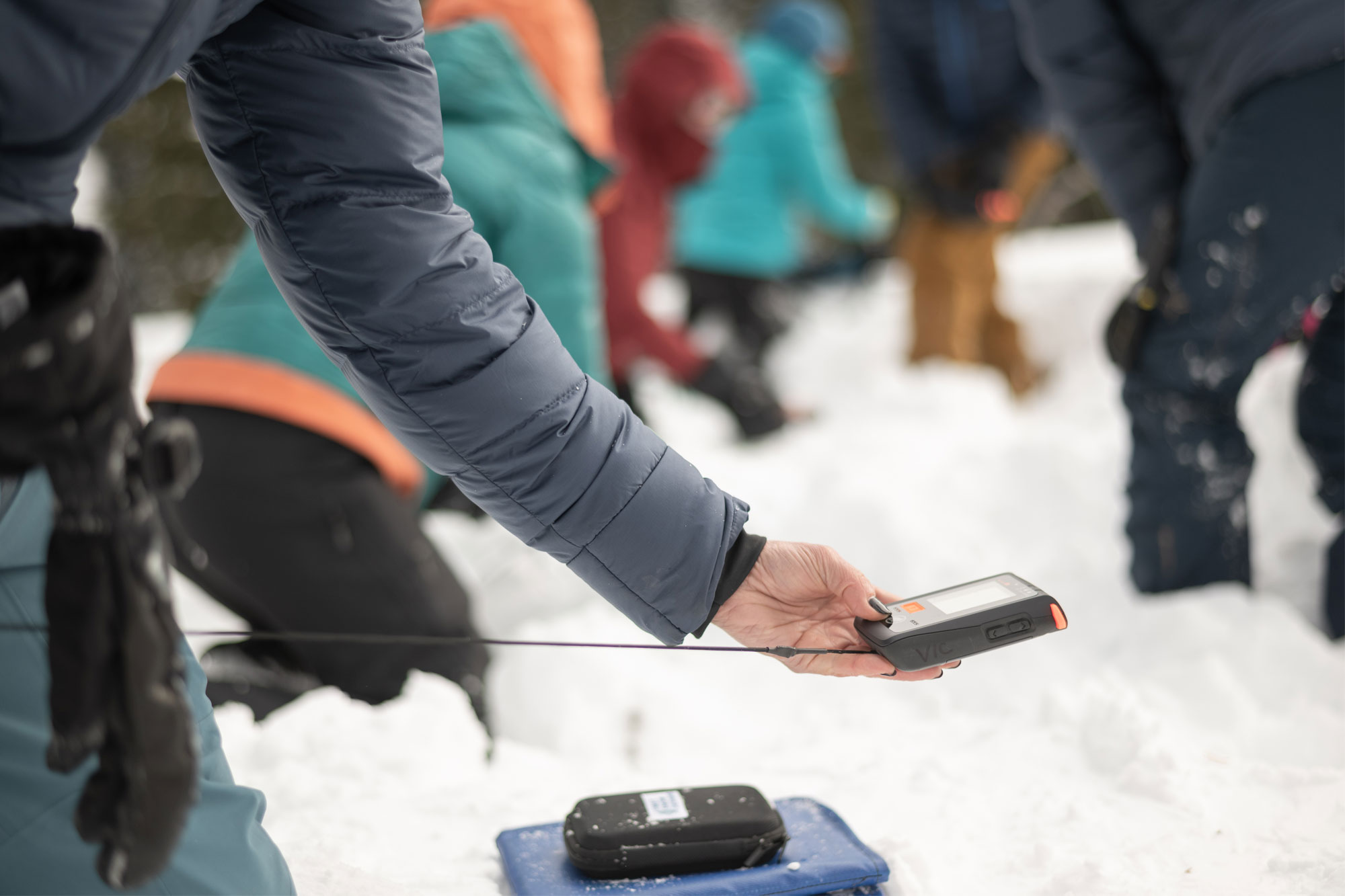 A woman in the snow using an avalanche transceiver