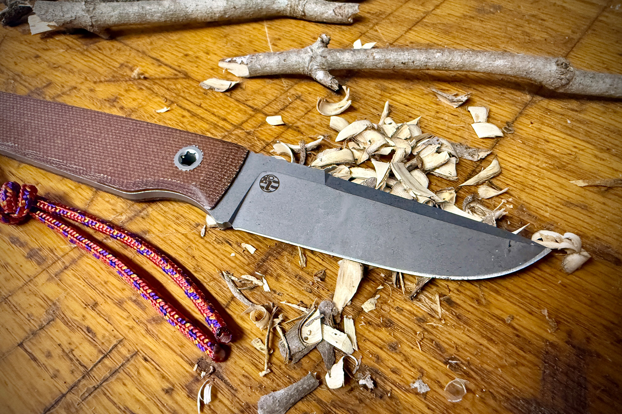 Wood shavings surround the Big Idea Design USA Signal on a wooden table after carving small sticks