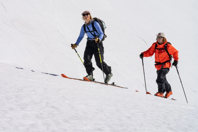 Two skiers ascend a snowy slope using touring gear with Zero G ski