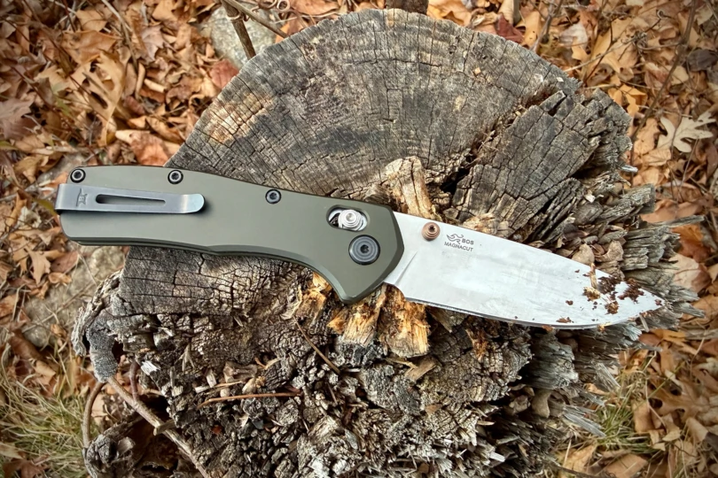 The Buck Knives Range Series knife lying on a broken tree stump with dirt on the blade after outdoor use