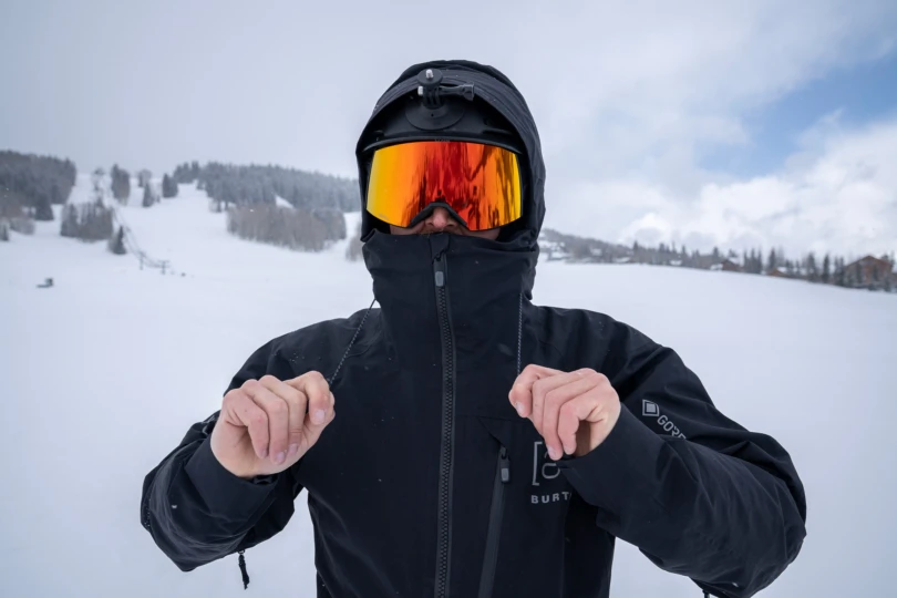 A snowboarder tightens the hood cords on the Burton snowboard jacket during snowfall