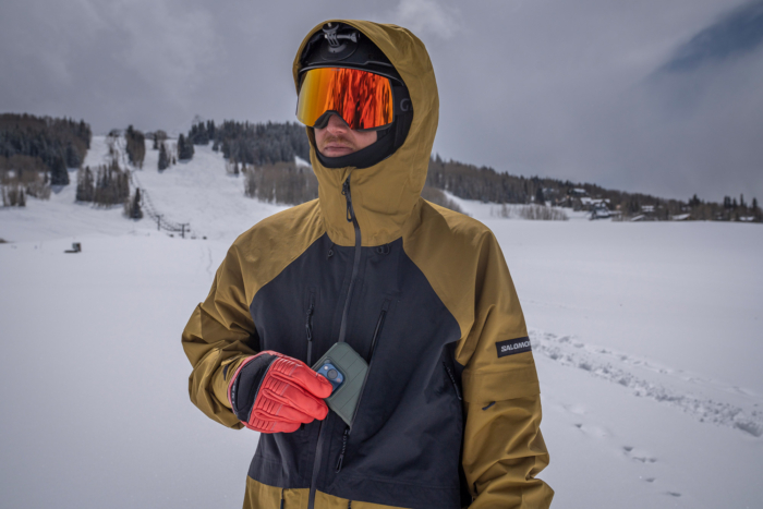 A rider pulls a phone from the chest pocket of the venom snowboard jacket