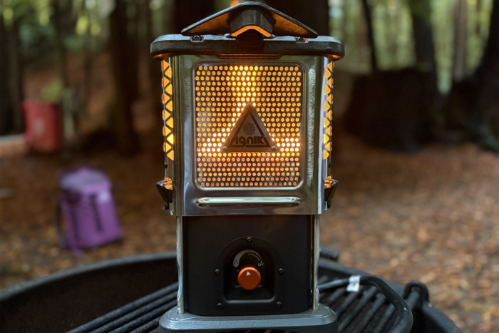 A close-up view of the Ignik Skullet Heater Stove glows with orange light through the front mesh panel