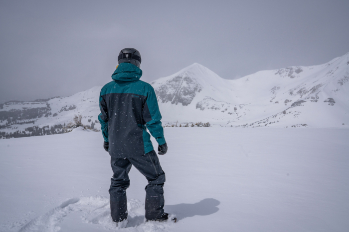 The rider faces the mountains, showing the back of the Jones Shralpinist Recycled GORE-TEX ePE Jacket