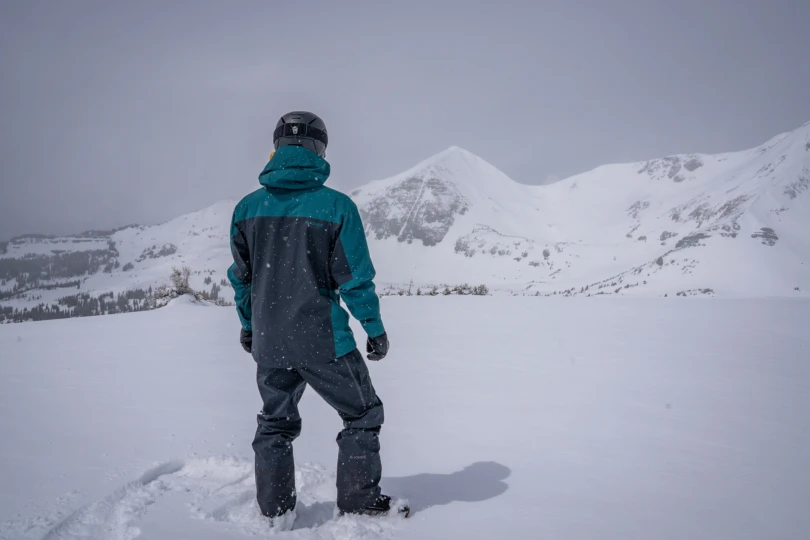The rider faces the mountains, showing the back of the Jones Shralpinist Recycled GORE-TEX ePE Jacket