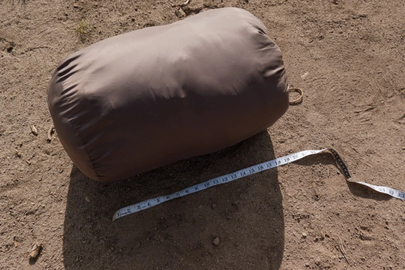 the packed siesta sleeping bag on the ground beside a ruler