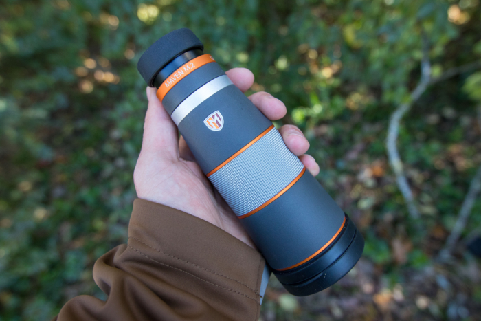 The Maven M.2 Monocular in a hand with vegetation in the background.