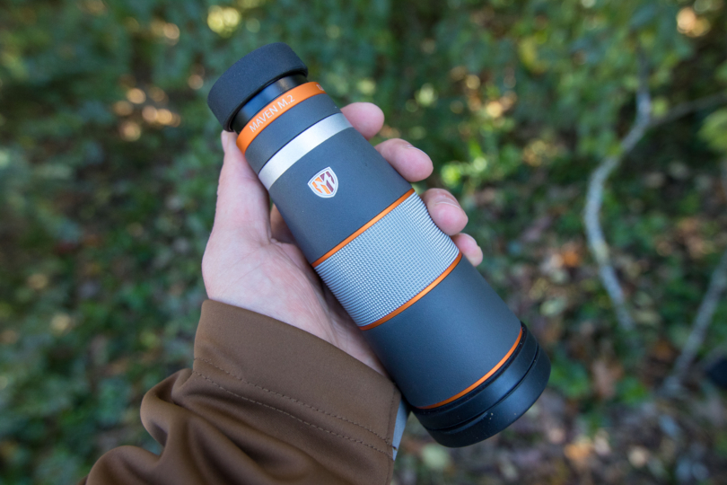 The Maven M.2 Monocular in a hand with vegetation in the background.