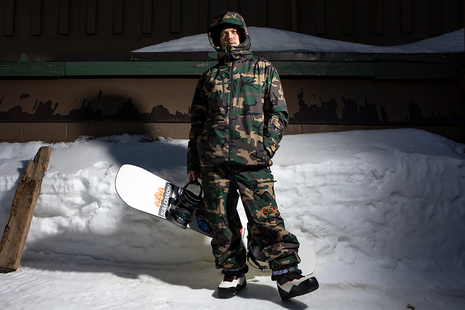 Person stands in front of snow in camo snowboard gear