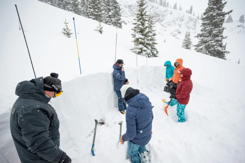 People an avalanche safety lesson in snowy mountain terrain