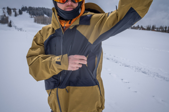A close-up shows the pit zip opened on the Salomon Venom Full Zip Jacket for airflow