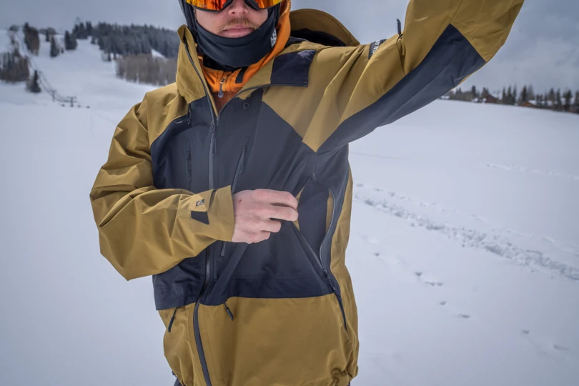 A close-up shows the pit zip opened on the Salomon Venom Full Zip Jacket for airflow