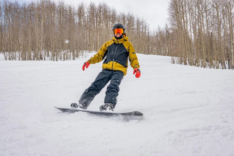 A snowboarder carves through soft snow while wearing a salomon jacket