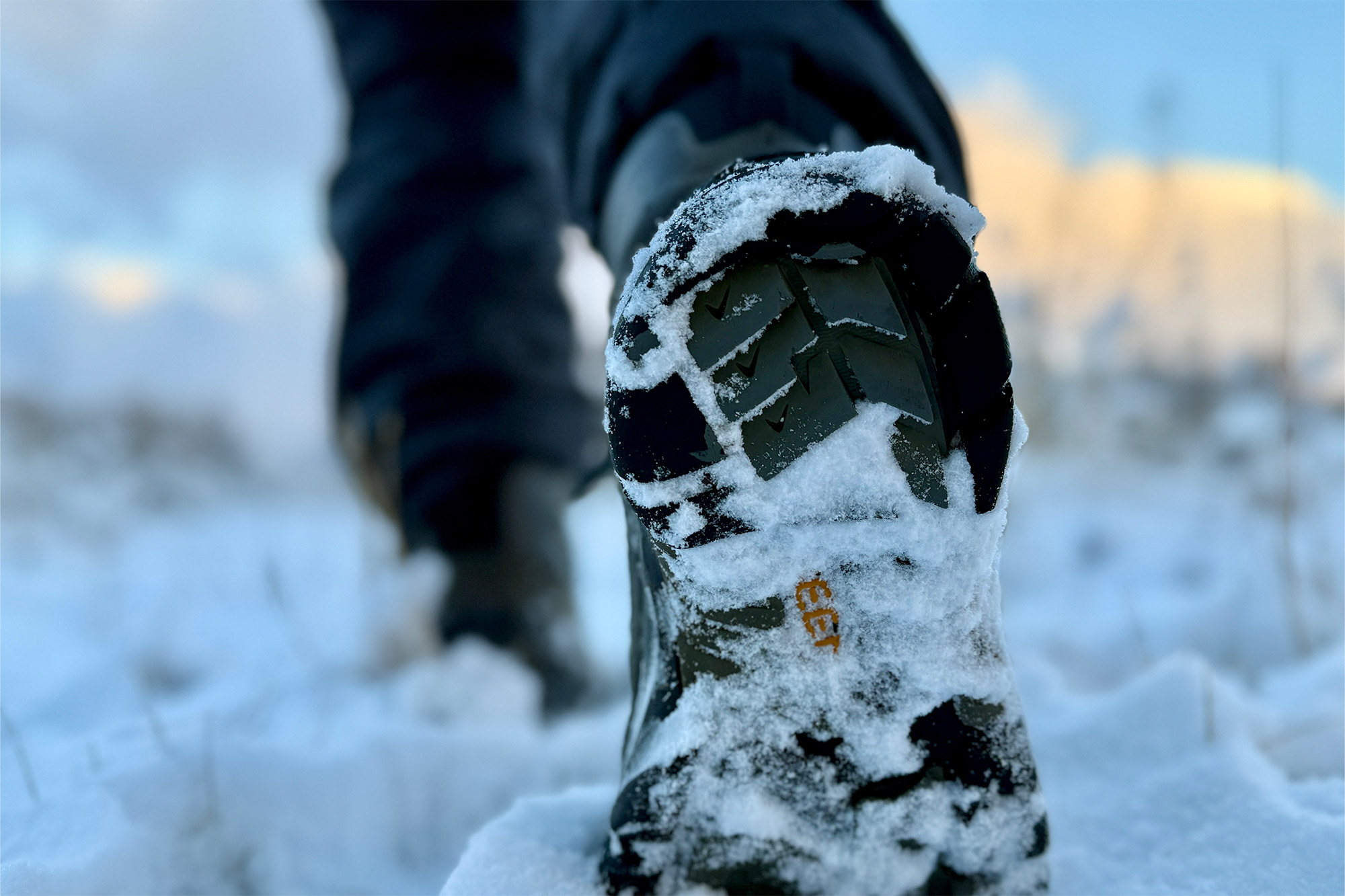 Snowy boot sole pressing into fresh powder, showing grip detail
