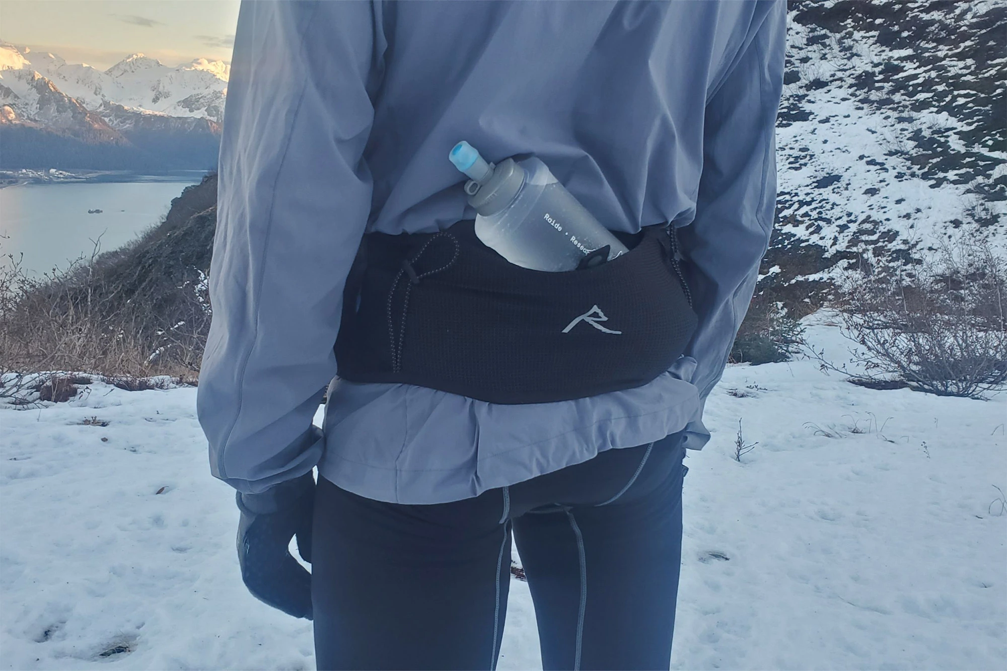 A runner standing in snow with a soft flask tucked into the back pocket of The Raide LF 2L around their waist