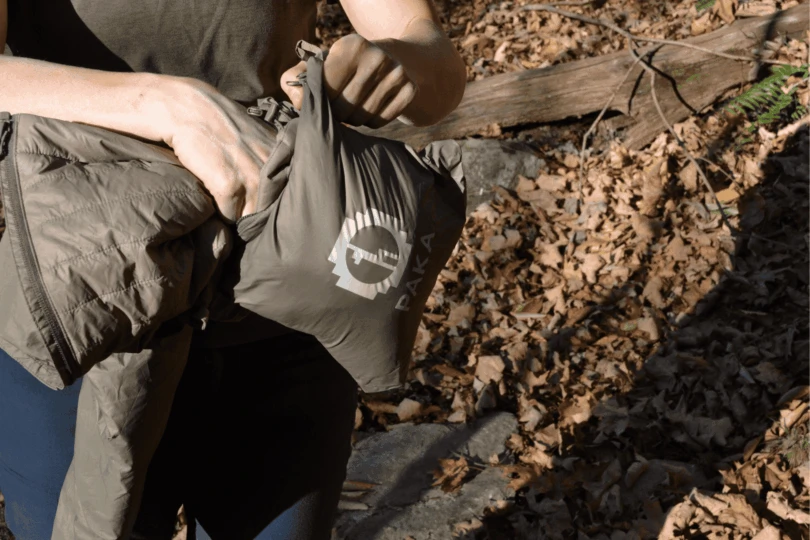 person stuffs jacket into stuff sack