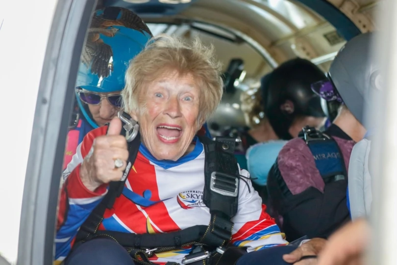 Woman in plane smiles with thumbs up
