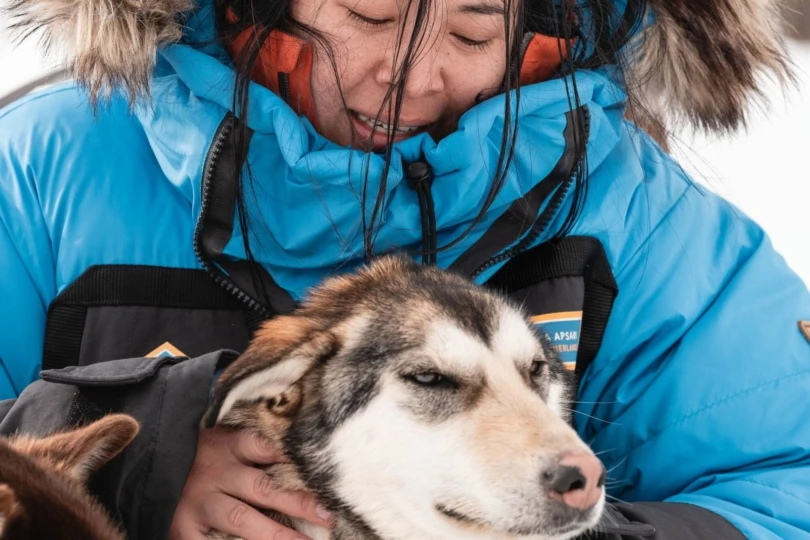 Close-up shot of woman in parka with husky sled dog 