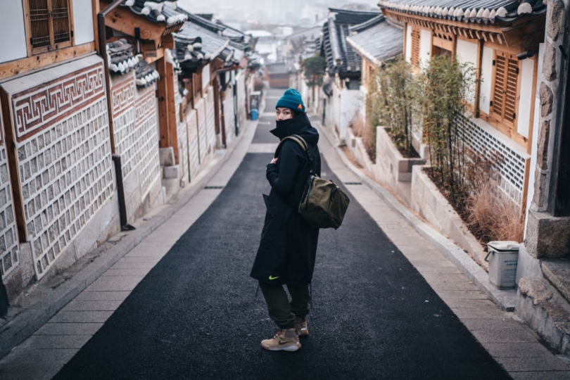 person stands in street wearing bag